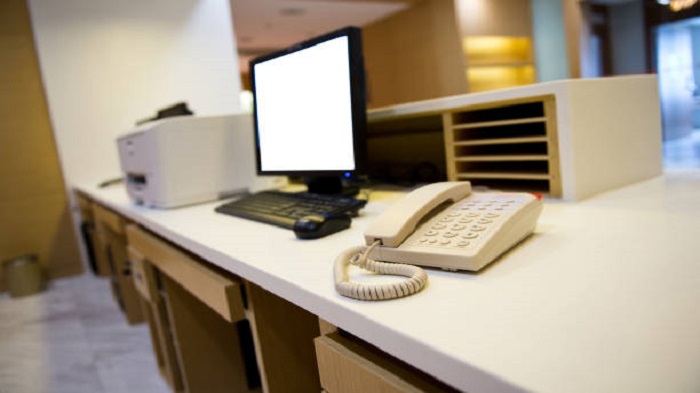 bureau d'une secrétaire médicale avec un ordinateur de bureau et un téléphone fixe-secrétaire médicale dédiée-Serenity