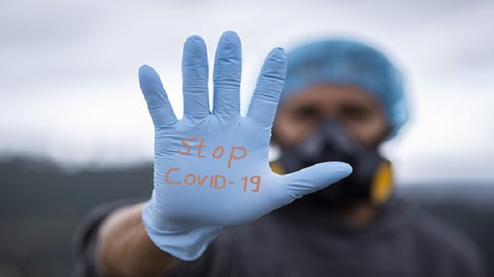 un homme portant des protection montrant le mot "stop Covid19" sur son gant comme signe d'avertissement - permanence téléphonique externalisée - Serenity