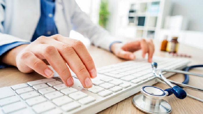 main d'un médecin tapant sur un clavier d'ordinateur à côté d'un stéthoscope - secrétaire médicale à distance - Serenity