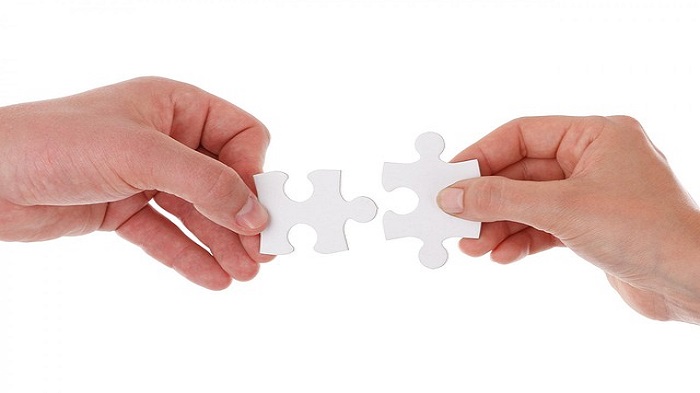 deux mains tenant deux pièces de puzzle qui se complètent - télésecrétariat médical externalisé - Serenity