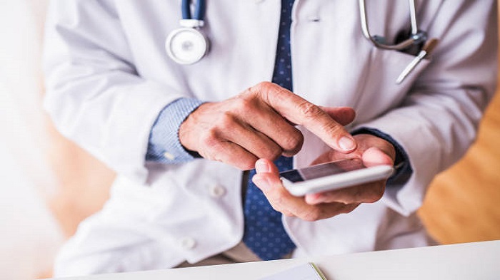 un professionnel de santé tenant un smartphone dans sa main - service de télésecrétariat médical à distance - Serenity