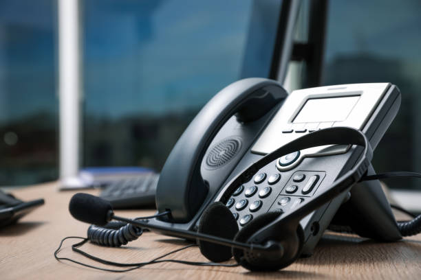 Téléphone fixe et casque d'écoute sur un bureau en bois à l'intérieur - accueil téléphonique médical - Serenity