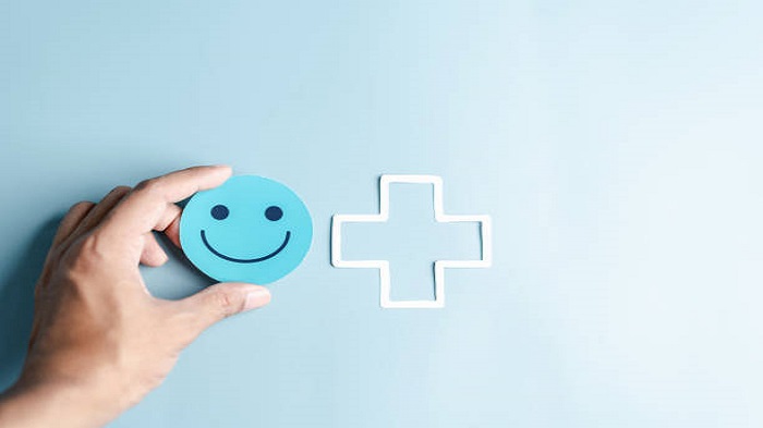 Mains tenant un visage souriant bleu heureux pour le concept de soins médicaux - tenue de dossiers médicaux - Serenity
