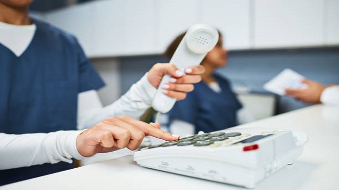 un réceptionniste médical composant un numéro de téléphone - centre d'expertise en télésecrétariat médical - Serenity