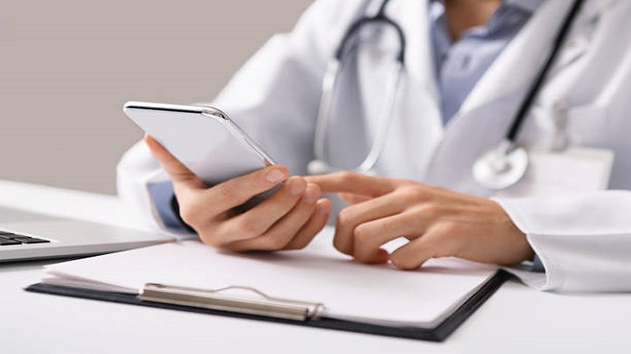 un docteur tenant un téléphone dans sa main sur son bureau - entreprise de télésecrétariat médical - Serenity