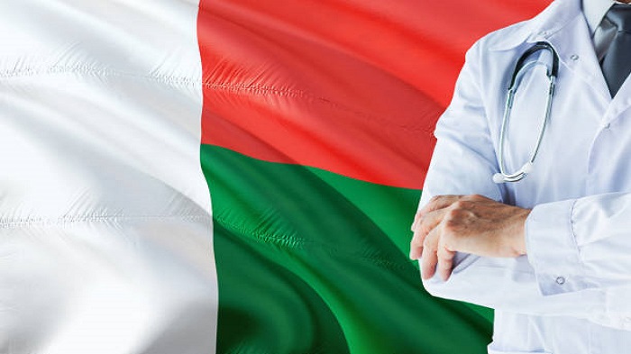 Médecin malgache debout avec un stéthoscope sur fond de drapeau malgache - secrétariat téléphonique Madagascar - Serenity